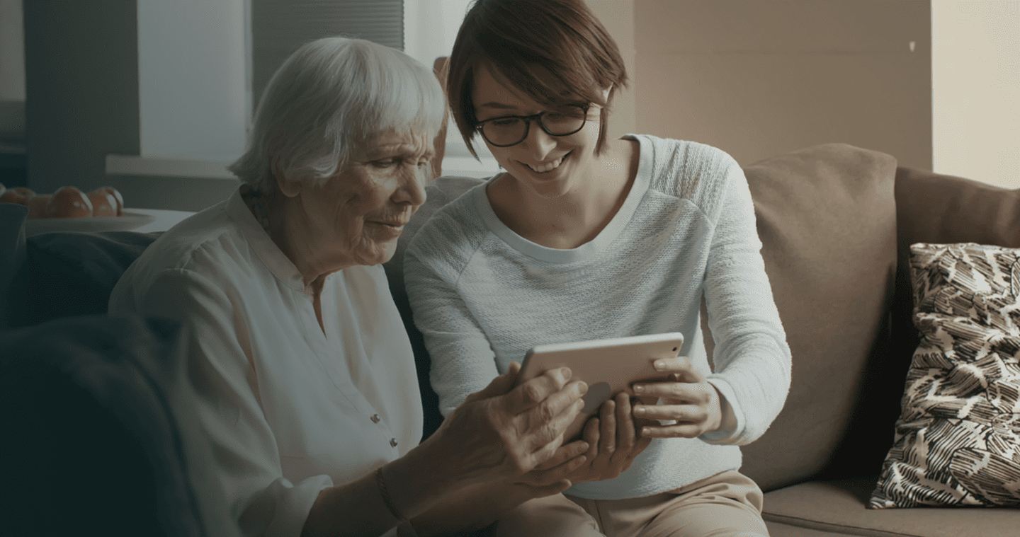 Hija mostrandole a su mamá anciana algo en el ipad.